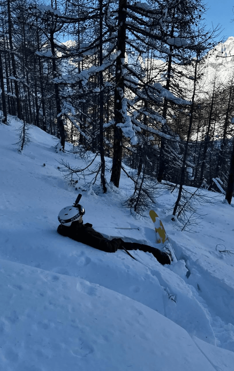 A skier resting in deep snow among the larches