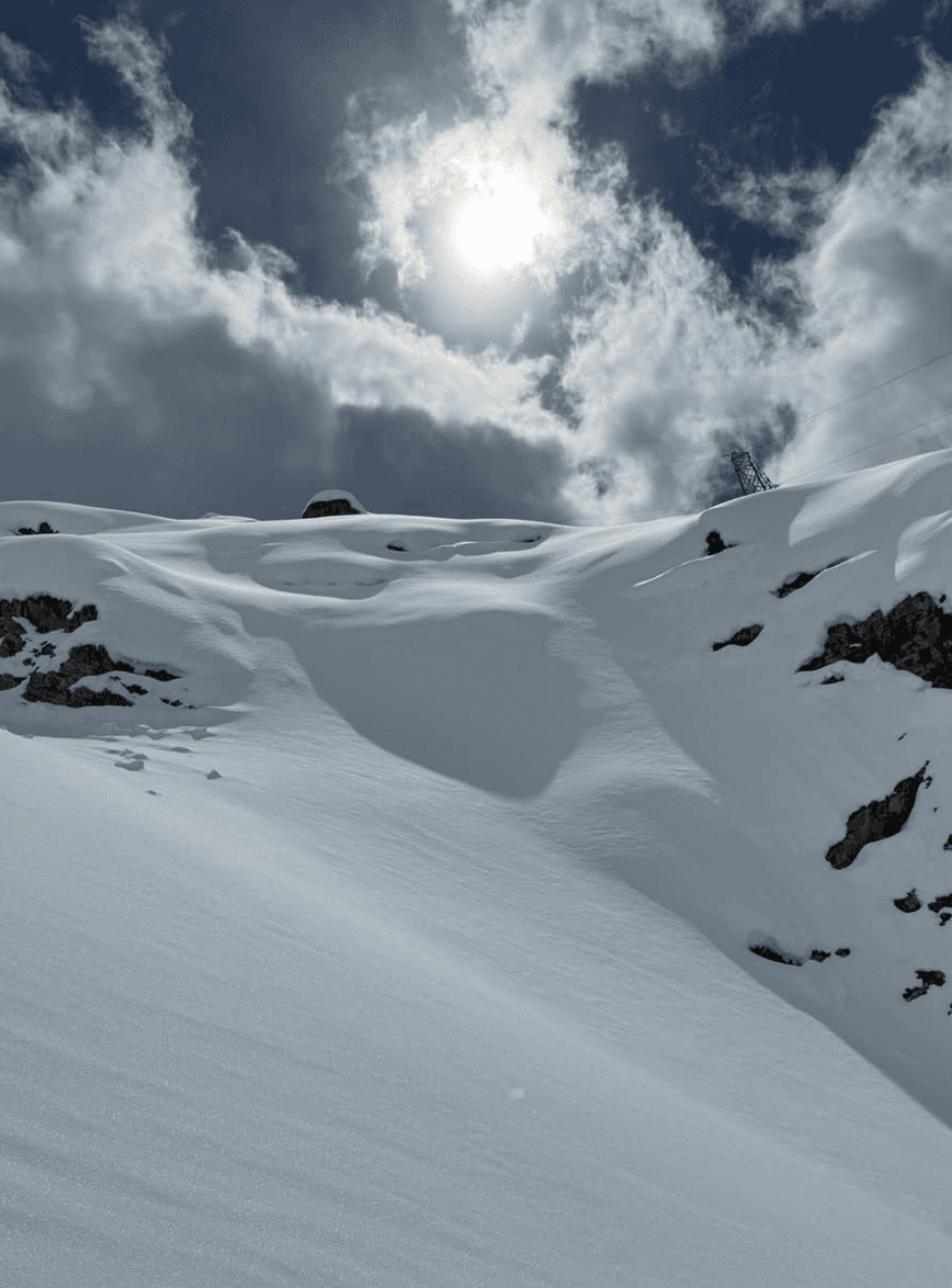 Sun breaking through cloud over snowfields high on the glacier